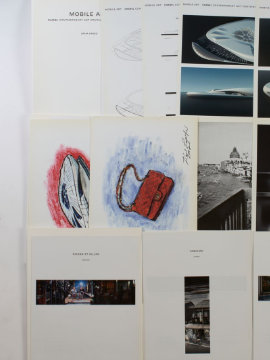 Eine Sammlung von Karl Lagerfeld skizzierten Notizen, farbigen Blättern und einem Buch auf einem Tisch.